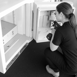 female locksmith repairing back panel of safe